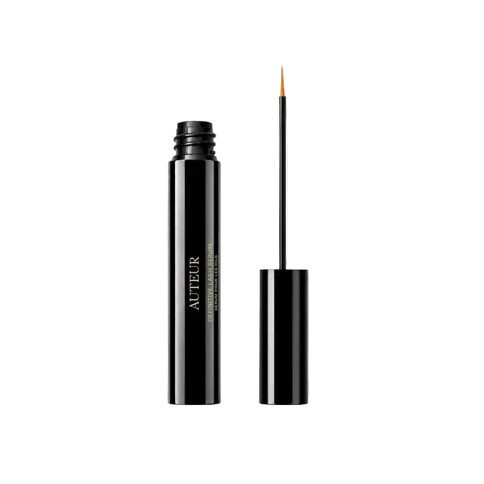 A black cosmetic tube with gold lettering stands next to its applicator wand on a clean white background. The tube displays the brand name 'AUTEUR' and the text 'THE PERFECTED CARE LIP GLOSS'.